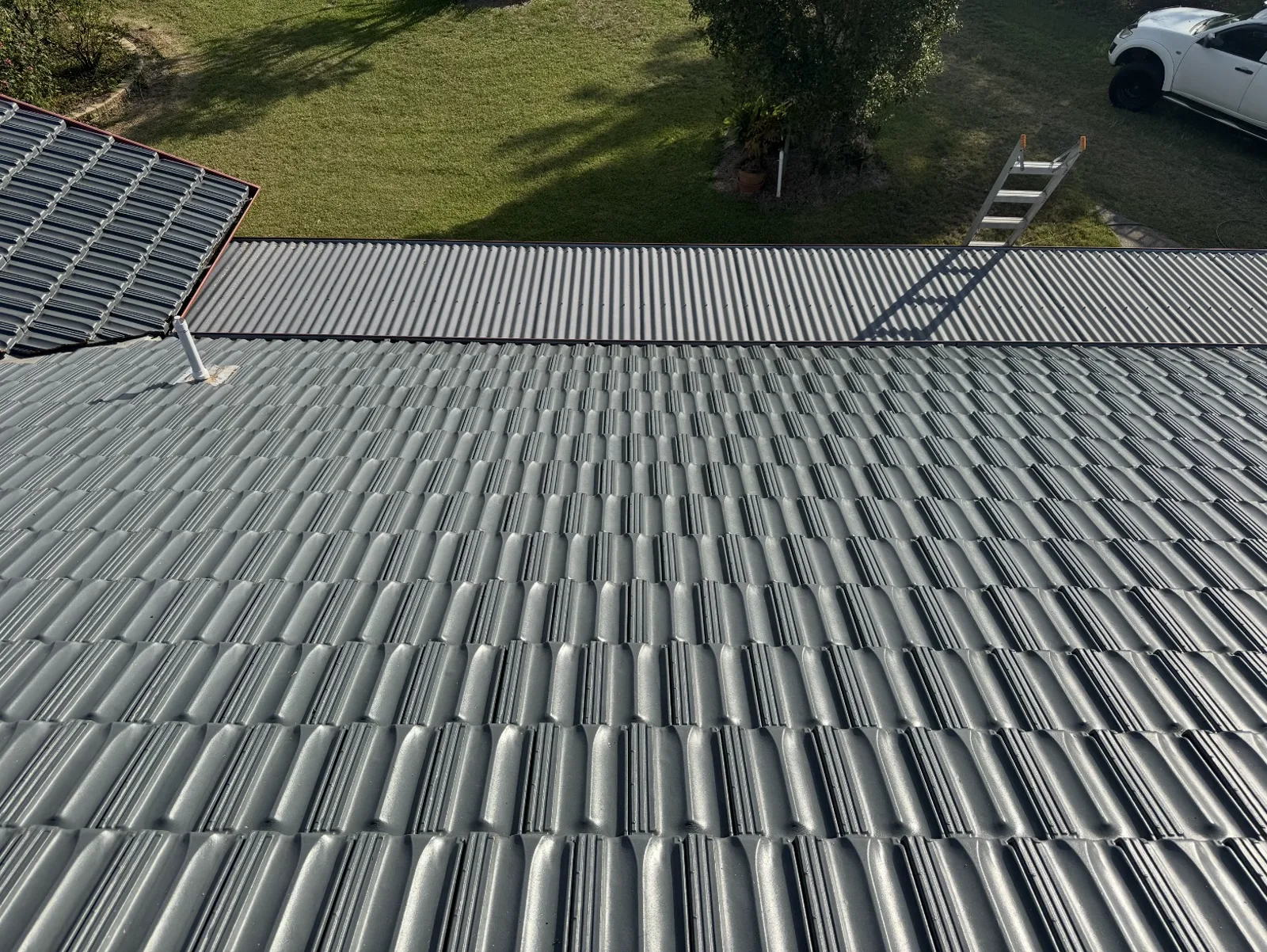Freshly soft-washed grey tile roof on a Newcastle home, with the Power Wash Empire ute and ladder in the yard